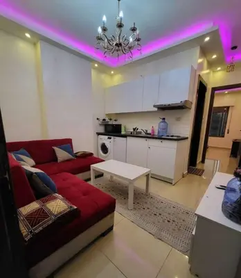 a living room with a red couch and a kitchen at MOTAMEZ APARTMENTS in Amman