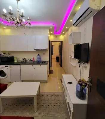 a kitchen with pink lights on the ceilings and a table at MOTAMEZ APARTMENTS in Amman
