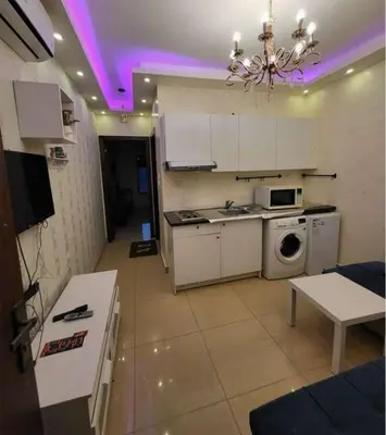 a kitchen with white cabinets and a washer and dryer at MOTAMEZ APARTMENTS in Amman