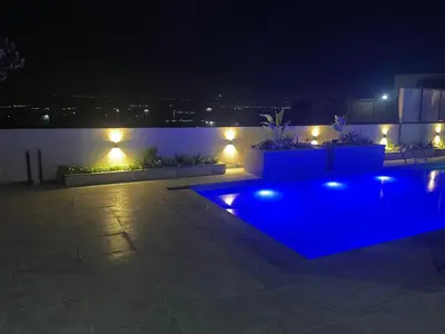 a backyard with a blue pool at night at Deadsea Elite First floor shared swimming pool in Sowayma