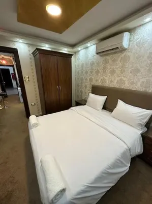 a bedroom with a large bed with white sheets at al-burj apart at 7th circle in Amman