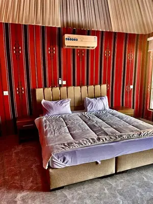 a bed in a room with a red wall at Wadi Rum Desert Tours and Glamping with Hussein in Wadi Rum