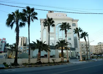 a building with palm trees in front of a street at Seraj Amman Hotel in Amman