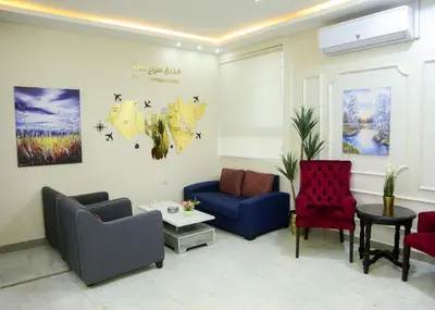 a living room with a blue couch and red chairs at Seraj Amman Hotel in Amman