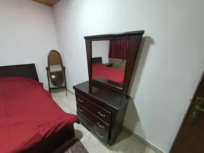 a bedroom with a red bed and a mirror at Maria Apartment in Amman