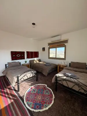 a room with three beds and a rug at Eman house in Wadi Musa