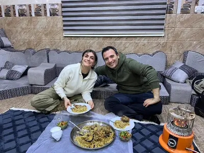 a man and woman sitting next to a table with food at Eman house in Wadi Musa