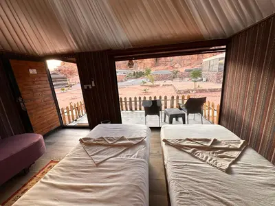 a room with two beds and a balcony with a table at Magical desert camp in Disah