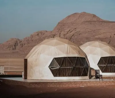 two domes in the desert with a mountain in the background at Abdul Rahman Wadi Rum in Wadi Rum