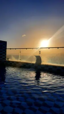 a swimming pool with the sun setting over the water at Alena Boutique Hotel in Aqaba