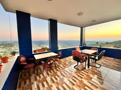 a balcony with tables and chairs and a view of the ocean at Al-Bustan House& Umm Qais in Um Qeis