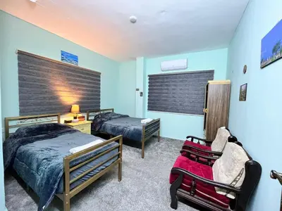 a bedroom with two beds and a chair in it at Al-Bustan House& Umm Qais in Um Qeis
