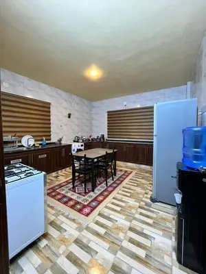 a kitchen with a table with chairs and appliances at Al-Bustan House& Umm Qais in Um Qeis