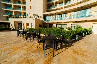 a patio with tables and chairs in front of a building at Oryx Hotel Aqaba in Aqaba
