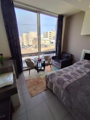 a bedroom with a bed and a table and a large window at Gentle Breeze Studio 2 in Amman