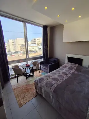 a bedroom with a bed and a table and a large window at Gentle Breeze Studio 2 in Amman
