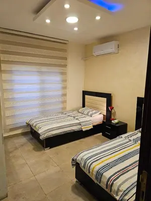 a bedroom with two beds and a window with a fan at Apartment no 30 in Amman