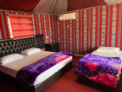 a bedroom with two beds with purple sheets and roses at Rum Bacific camp in Wadi Rum
