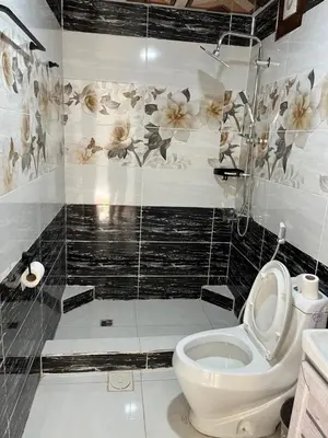 a bathroom with a toilet and flowers on the wall at Rum Bacific camp in Wadi Rum