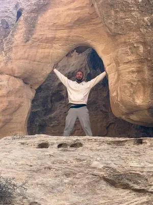 a man standing inside of a rock cave at Dana local life Eco Lodge in Dana