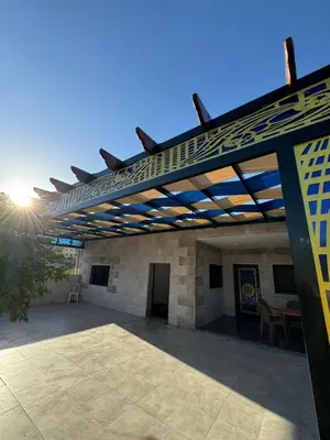 an outdoor patio with a wooden pergola at البيت الريفي in Jerash