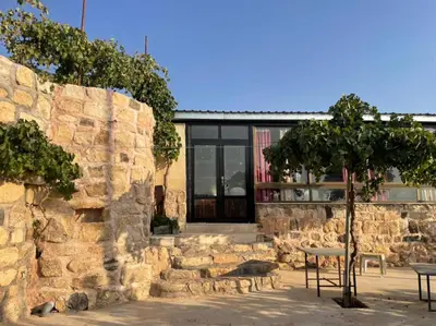 a stone building with a table and a tree at Al-Karak Countryside and hotel in Ad Dimnah