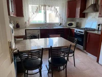 a kitchen with a table and chairs and a stove at Khalda Renovated 3 Bedroom Apartment in Amman