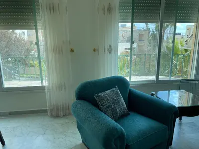 a blue chair in a living room with windows at Khalda Renovated 3 Bedroom Apartment in Amman