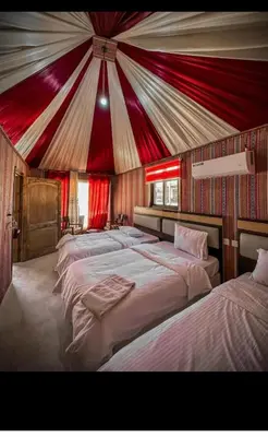 two beds in a room with a red and white tent at Glow of Wadi Rum Camp in Wadi Rum