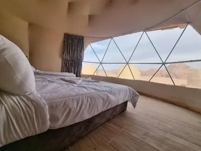 a bedroom with a bed and a large window at Glow of Wadi Rum Camp in Wadi Rum