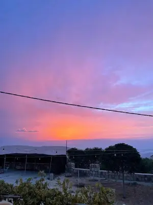 a sunset over a field with a building and a power line at Heritige Inn Jordan in Ad Dimnah