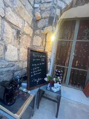 a sign in front of a stone building with a table with a chalkboard at Heritige Inn Jordan in Ad Dimnah