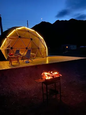 a tent with two chairs and a table next to a fire at Desert Boulevard Camp in Wadi Rum