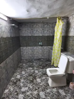 a dirty bathroom with a toilet and a yellow shower curtain at Mickey Mouse studio in Jerash