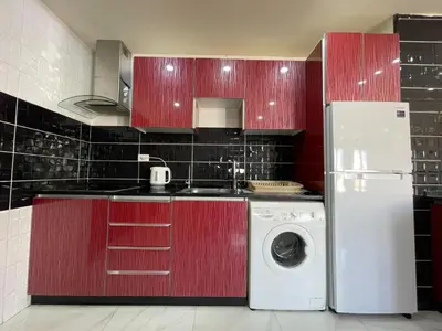 a kitchen with red cabinets and a washing machine at Modern 2-Bedroom Apartment in a Vibrant Neighborhood in Amman