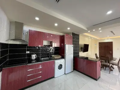 a kitchen with red cabinets and a white refrigerator at Modern 2-Bedroom Apartment in a Vibrant Neighborhood in Amman