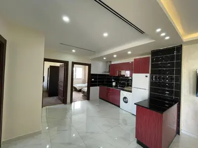 a kitchen with red cabinets and a white refrigerator at Modern 2-Bedroom Apartment in a Vibrant Neighborhood in Amman