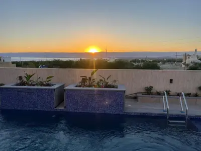 a swimming pool with a sunset in the background at Deadsea Elite second floor shared swimming pool in Sowayma