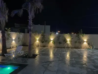a patio at night with a chair and palm trees at Deadsea Elite second floor shared swimming pool in Sowayma