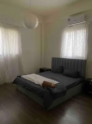 a bed in a bedroom with two windows at 3bedrooms apt near paris square in Amman