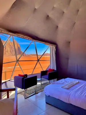 a bedroom with a bed and chairs and a large window at Wadi Rum Magic Stars in Wadi Rum