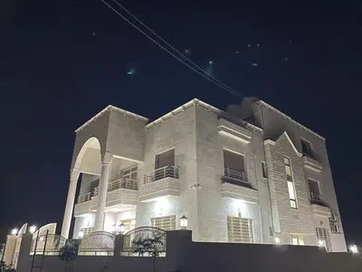 a large white building at night with lights at Airport Villa Amman in Amman