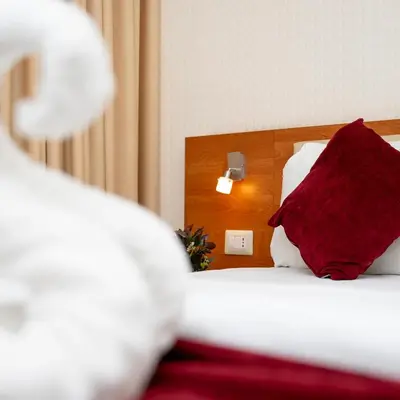 a bed with a red pillow on top of it at Sama Paris Plaza Hotel in Amman