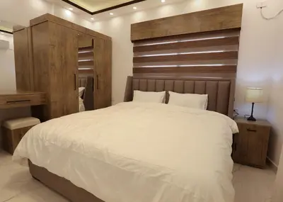 a bedroom with a large white bed with a wooden headboard at Third circle Luxury Hotel apartment in Amman