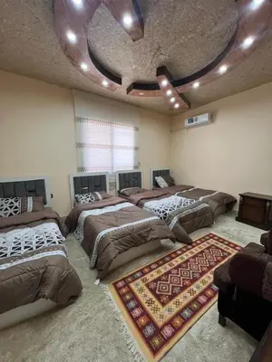 a large room with four beds and a rug at Bedouin family home in Wadi Musa