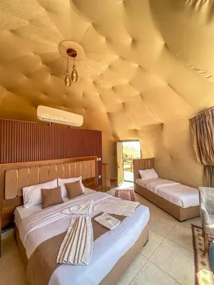 a bedroom with two beds and a ceiling with logs at RUM ARIZONA lUXURY CAMP in Wadi Rum