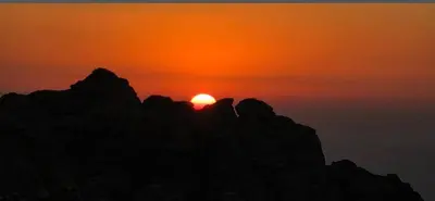 a sun setting on the top of a mountain at Dana Village Lodge in Dana