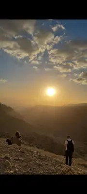 two people standing on a mountain looking at the sunset at Dana Village Lodge in Dana