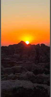 a sunset in the desert with the sun setting at Dana Village Lodge in Dana
