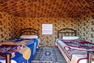 two beds sitting in a room with wallpaper at Wadi Rum Backpacker Camp in Wadi Rum